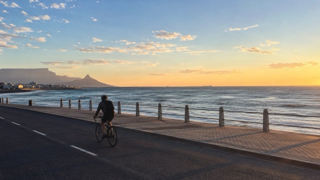 Man cycling at sunrise on a Cape Town promenade